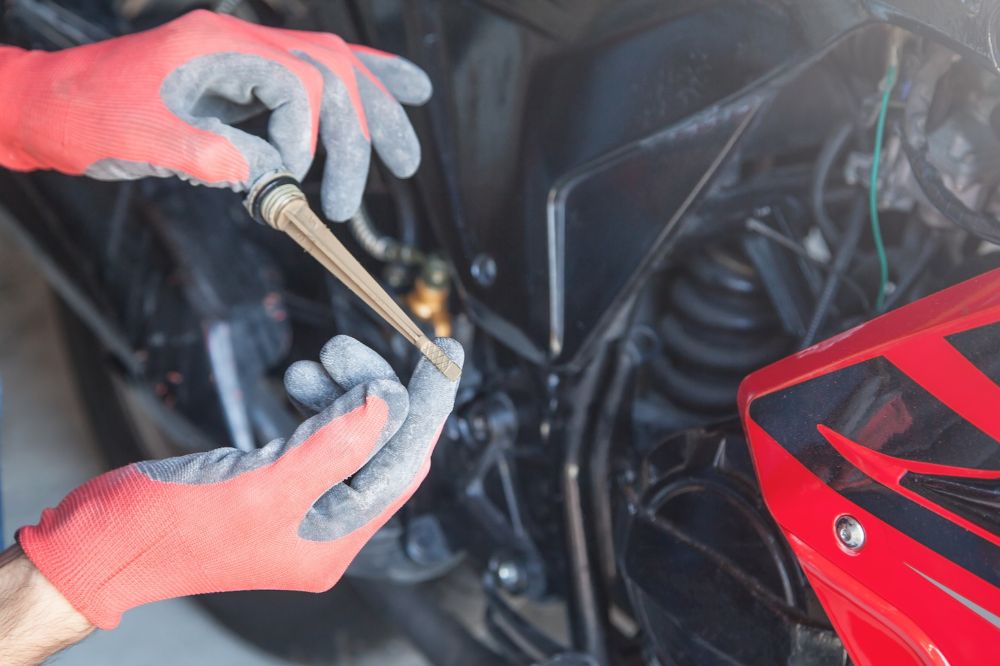 Mechanik kontroluje hladinu motorového oleja v motorke