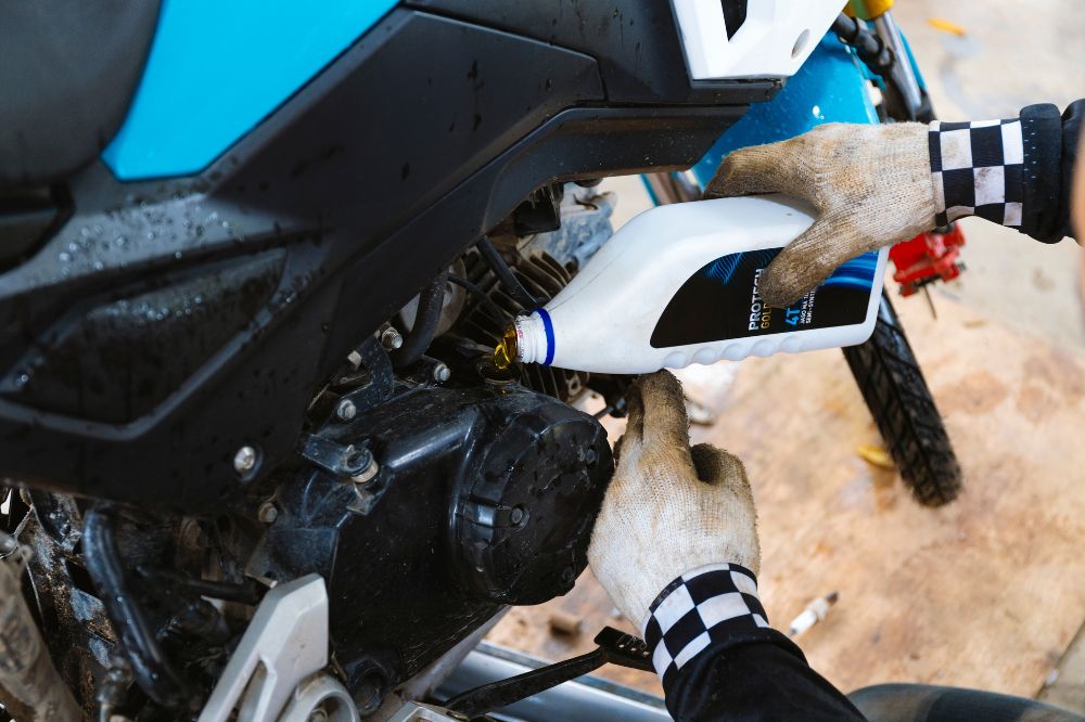 Motork&aacute;r v gar&aacute;ži dolieva olej do svojej motorky