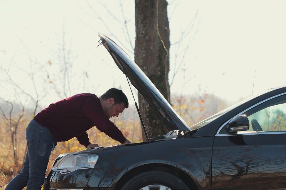 Muž pri otvorenej kapote rie&scaron;i poruchu motora
