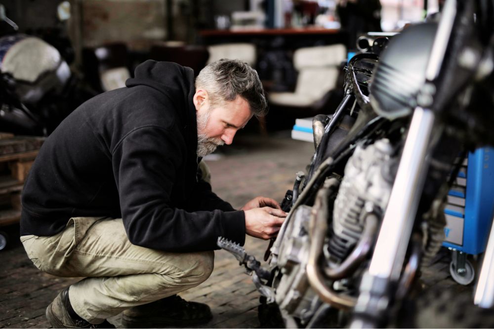 Muž v gar&aacute;ži kontroluje d&ocirc;ležit&eacute; s&uacute;časti motorky